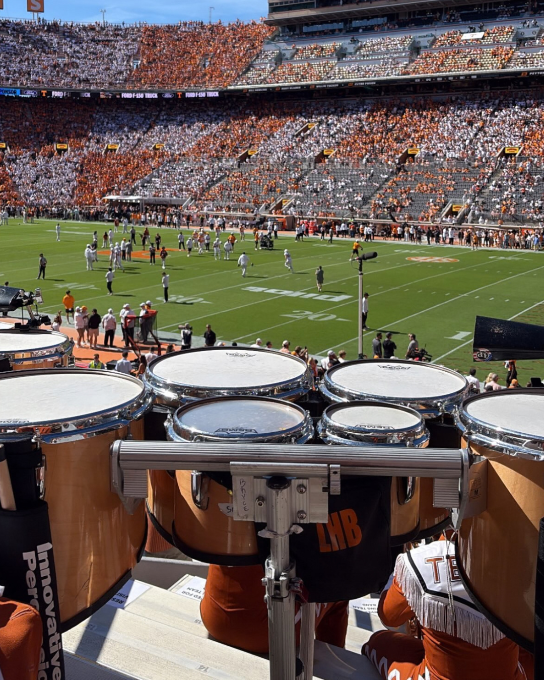 image with drums in the foreground with a football field in the back