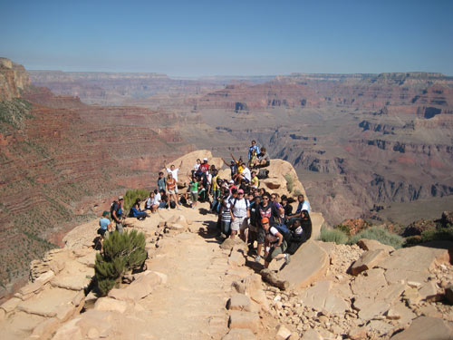 Students in GeoFORCE Texas wave from a cliff overlooking the Grand Canyon.
