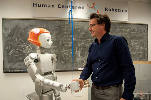 Assistant Professor Luis Sentis shakes hands with Dreamer the robot.