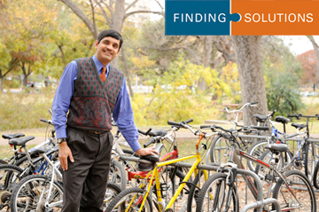 Chandra Bhat standing with lots of bicycles
