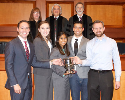 Group shot of winning UT Law mock trial team with their trophy and the competition judges
