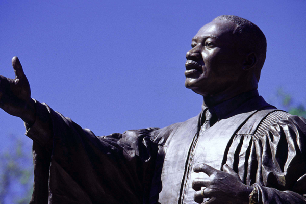 Statue of Martin Luther King Jr. reaching for the future against a clear blue sky.