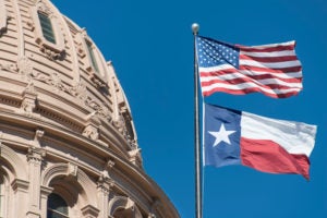 Texas Capitol Dome on the left with the American and Texas flags waving on the left.