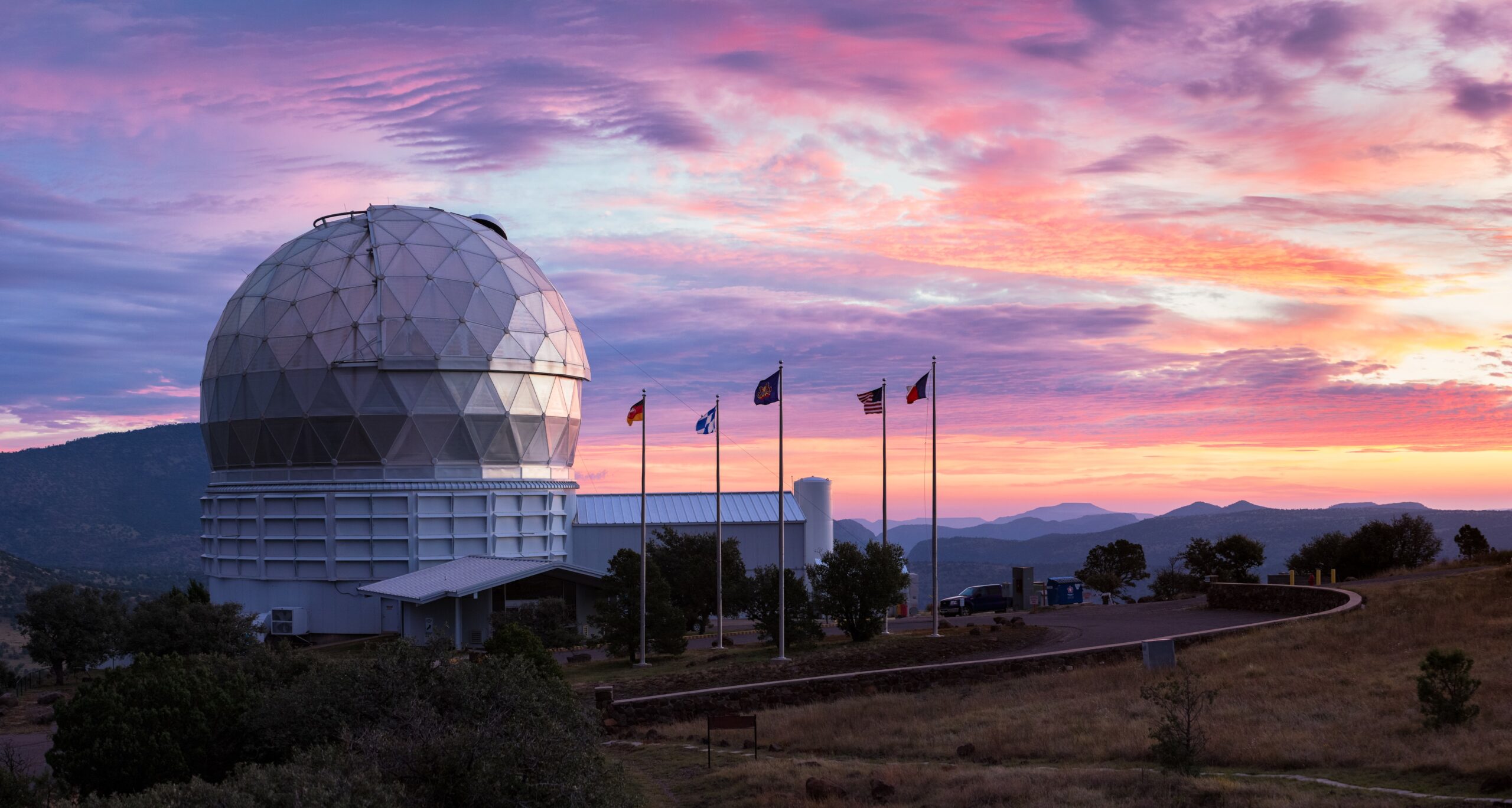 The dome of the Hobby-Eberly Telescope sits at left with a backdrop of a multi-colored West Texas sunset.