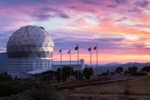 The dome of the Hobby-Eberly Telescope sits at left with a backdrop of a multi-colored West Texas sunset.