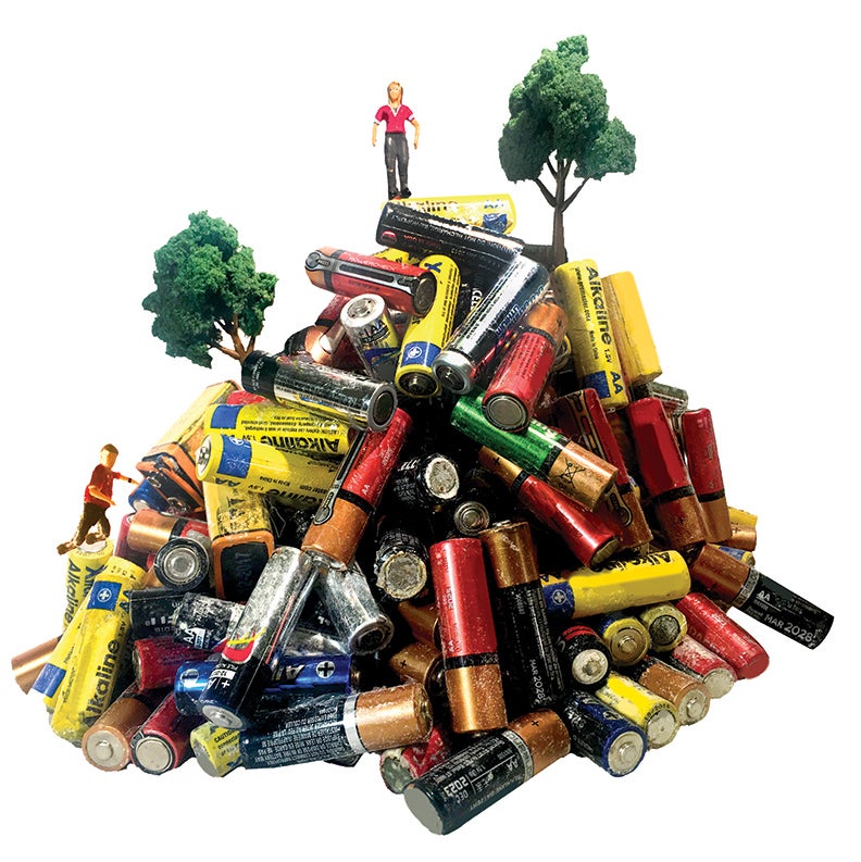 A pile of used batteries with small figures of people and trees.