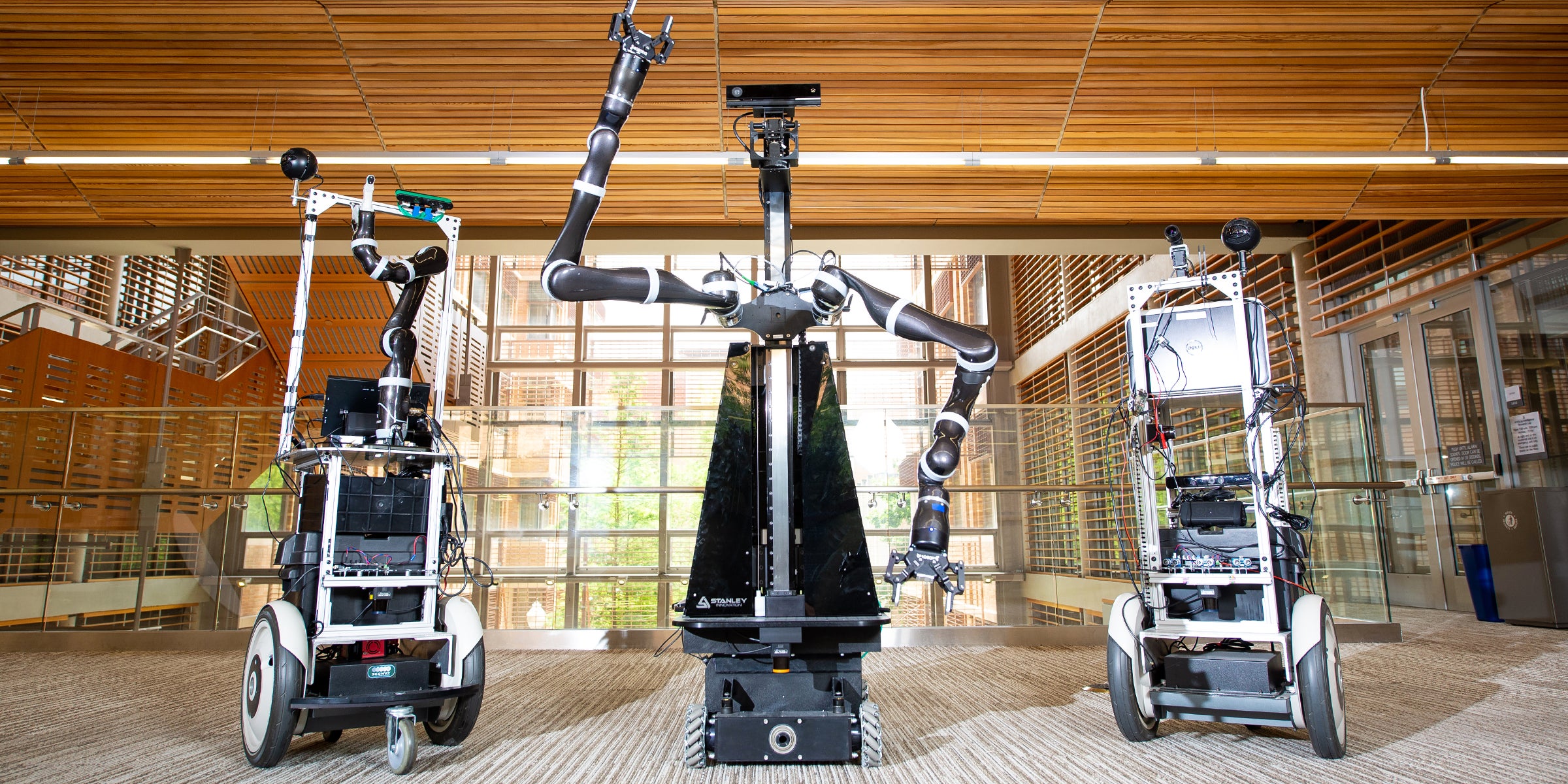 Two Building-Wide Intelligence Project (BWI) robots flank a robot from the Personal Autonomous Robotics Lab (PeARL), center, in the GDC at The University of Texas at Austin. Two Building-Wide Intelligence Project (BWI) robots flank a robot from the Personal Autonomous Robotics Lab (PeARL), center, in the GDC at The University of Texas at Austin.