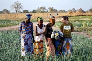 Student in the field with female farmers in Africa.