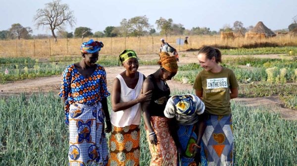 Student in the field with female farmers in Africa.