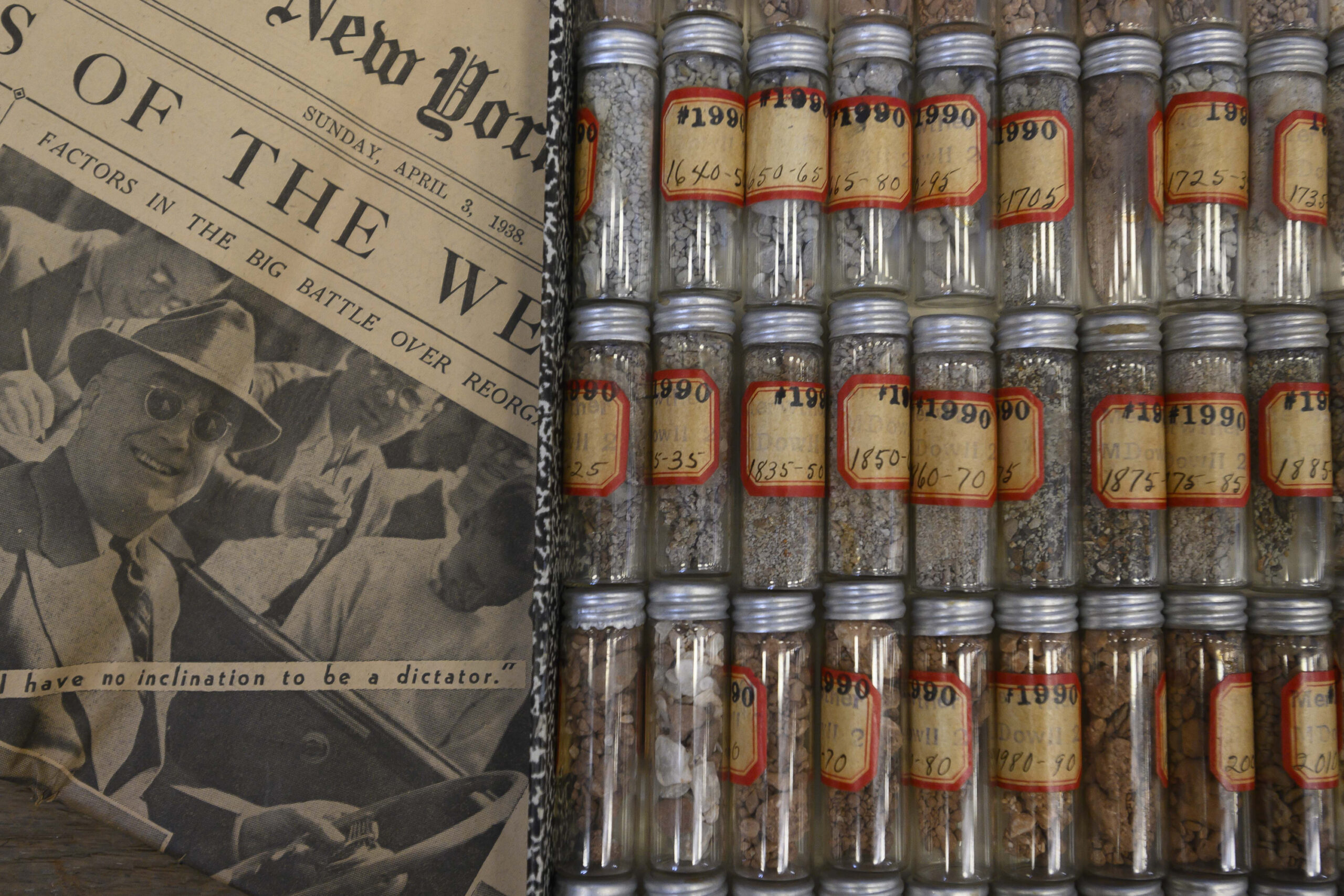 Tiny clear glass vials that show the cuttings, with a newspaper from 1937 with President Franklin D. Roosevelt on the front page.
