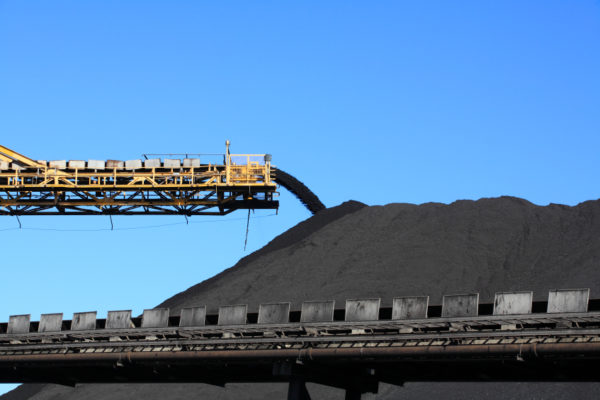 a large yellow conveyor belt carrying coal and emptying onto a huge