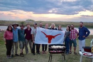 Students holding Longhorn flag at excavation site.