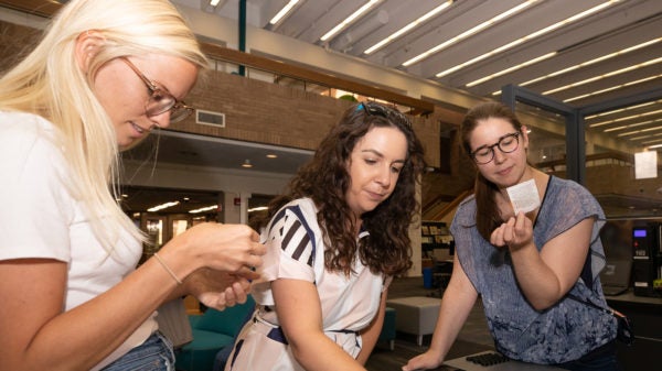 Three women looking at small 3D printed models.