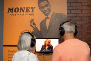 Two people wearing headphones listen to a video interview.