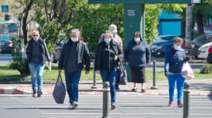 A group of people cross street with masks on.