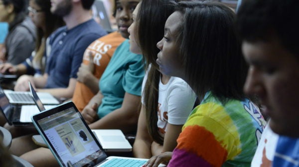 Woman with laptop listens in classroom