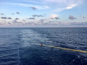 A photograph of the ocean showing a seismic streamer trailing in the ocean.