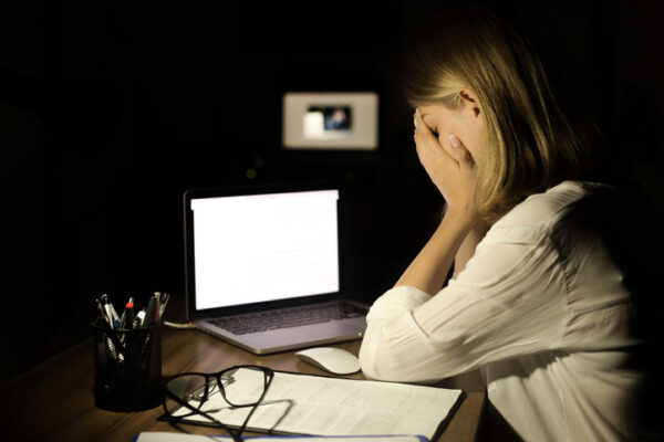Depressed woman working with computer at night
