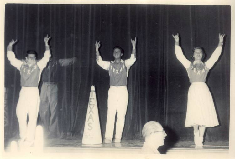 Two male cheerleaders and one female cheerleader do Hook'em Horns sign in black and white photo
