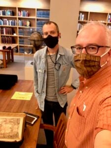 Selfie of two men in masks with old book