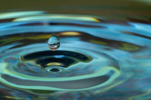 Water drop falling and impacting on a body of water close up