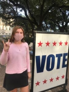 Soren Ettinger DeCou stands next to a sign reading VOTE