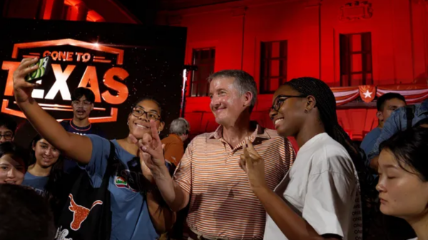 Jay Hartzell poses with two UT students in front of the UT Tower