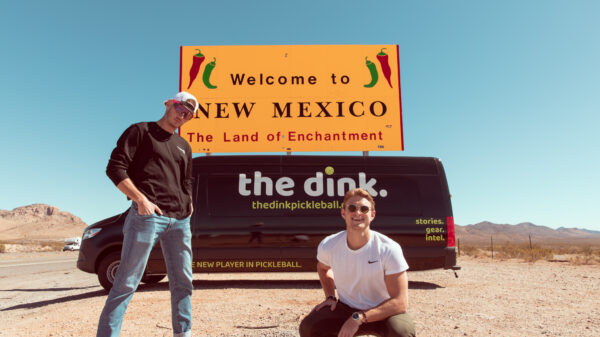 Young men in front of van with wrap reading the dink at New Mexico state line