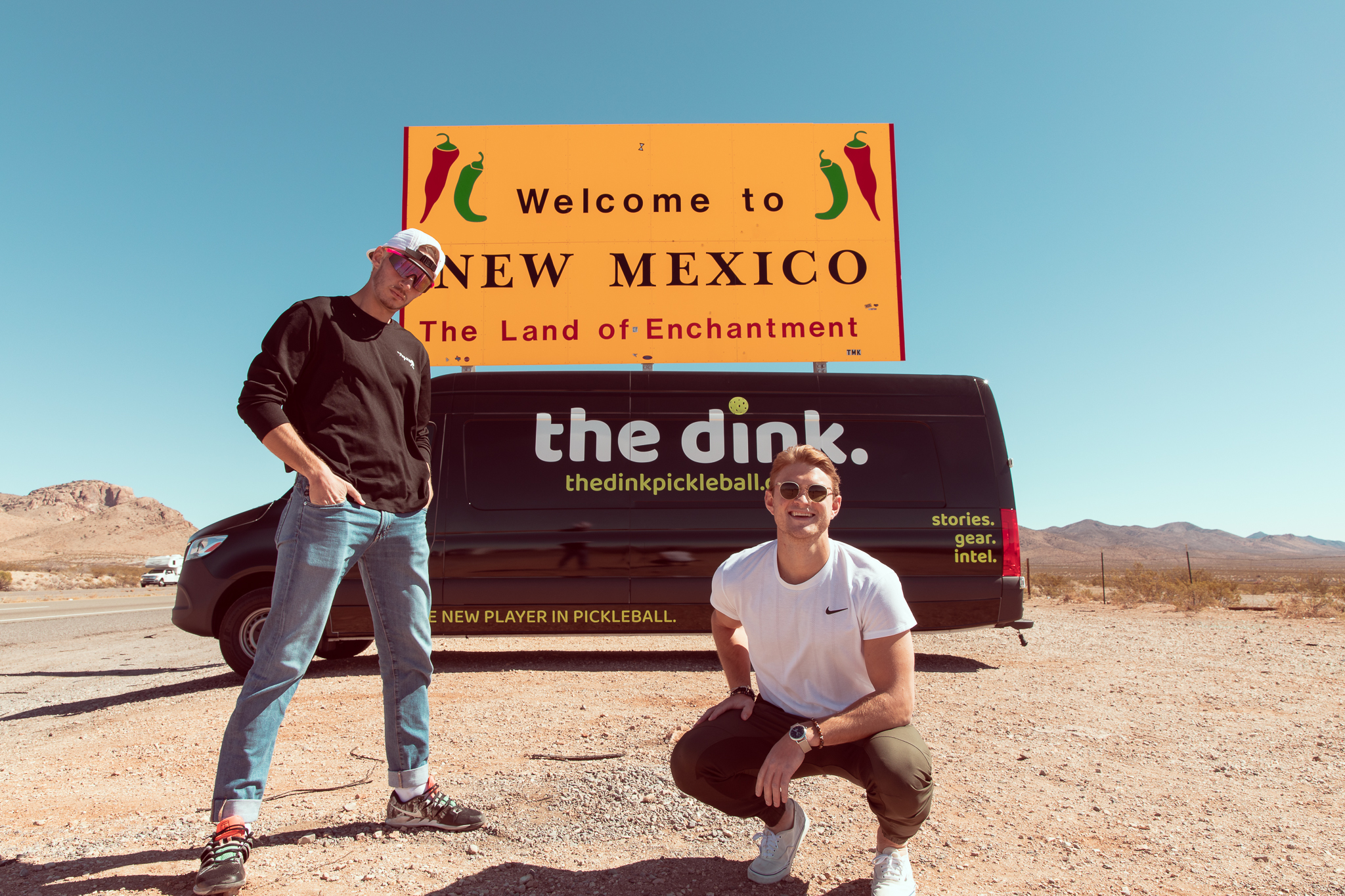 Young men in front of van with wrap reading the dink at New Mexico state line