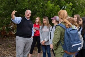 John Bartholomew with students outside pointing to something in the distance