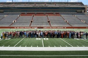 UT alumni, recipients of Texas Exes' Longhorn 100 awards, stand on the field and pose for a group photo in DKR Stadium.