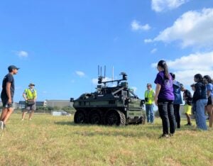 group of people look at an army tank in a field outside