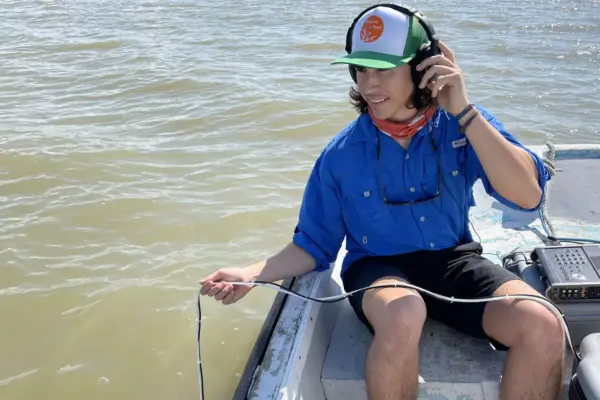 doctoral student philip souza uses a mobile hydrophone in a boat on the water to listen to fish on the Texas Gulf Coast
