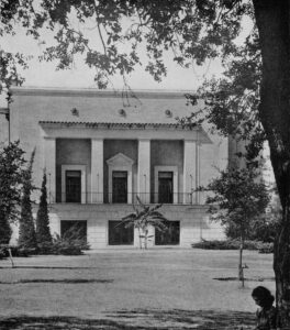 Black and white photo of the front view of the auditorium with a banana tree. 