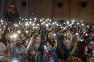 Students hold phone lights aloft