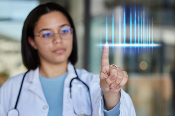 A young doctor in a white coat and stethoscope holds up a finger and gazes at lines of code at her fingertip