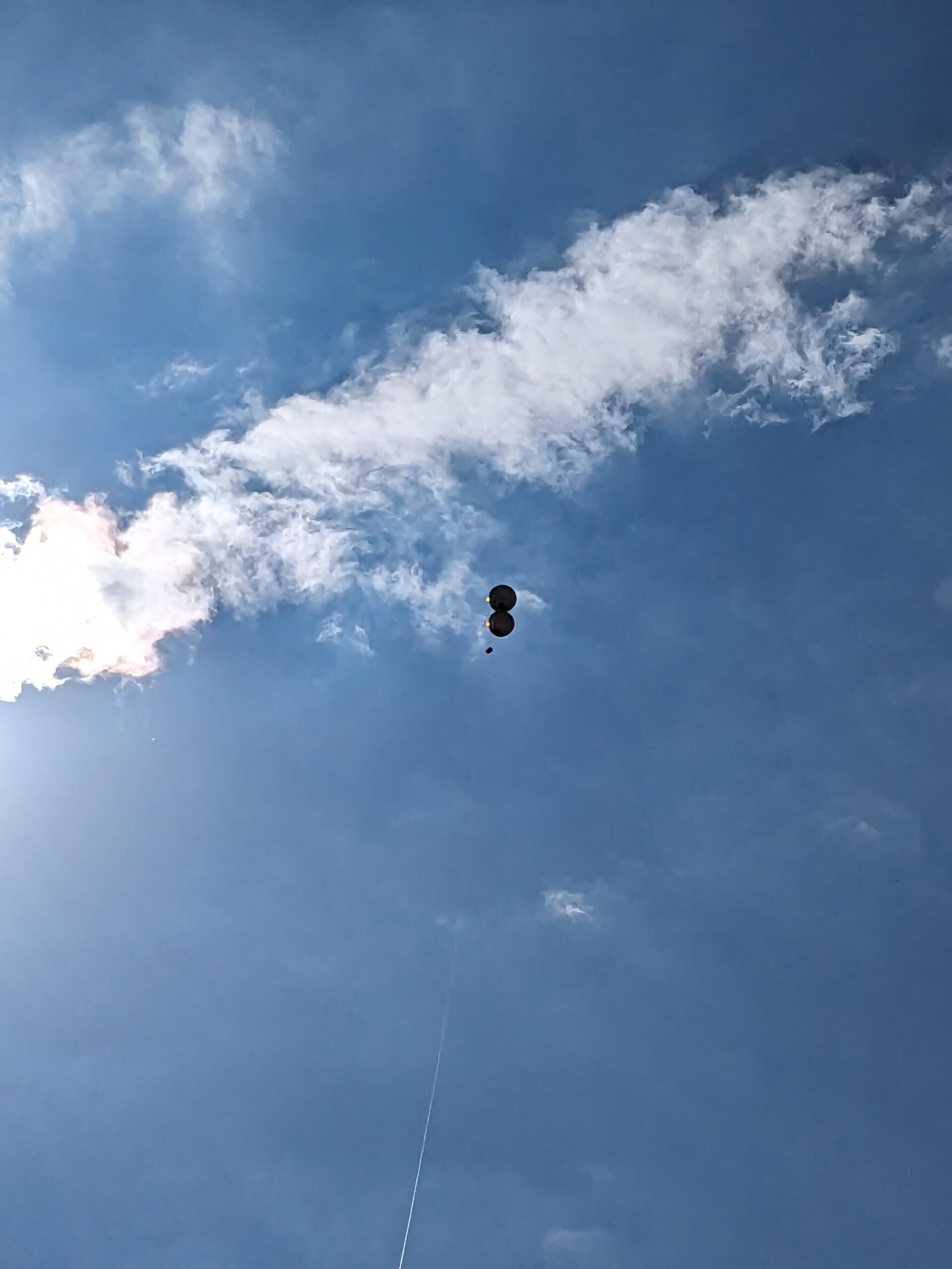 view from ground of sky and clouds with balloons floating in air