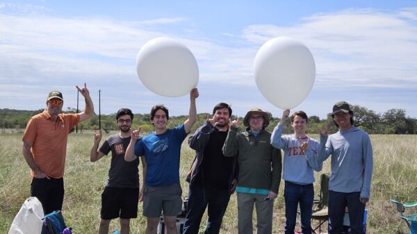 group of students posing in a field with balloons for texas eclipse ballooning project