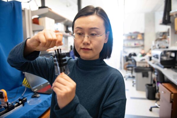 Lu stretches a index-card size piece of the electronic skin while in the lab.