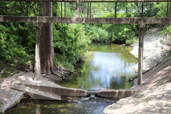 A view of Waller Creek with a bridge above it.