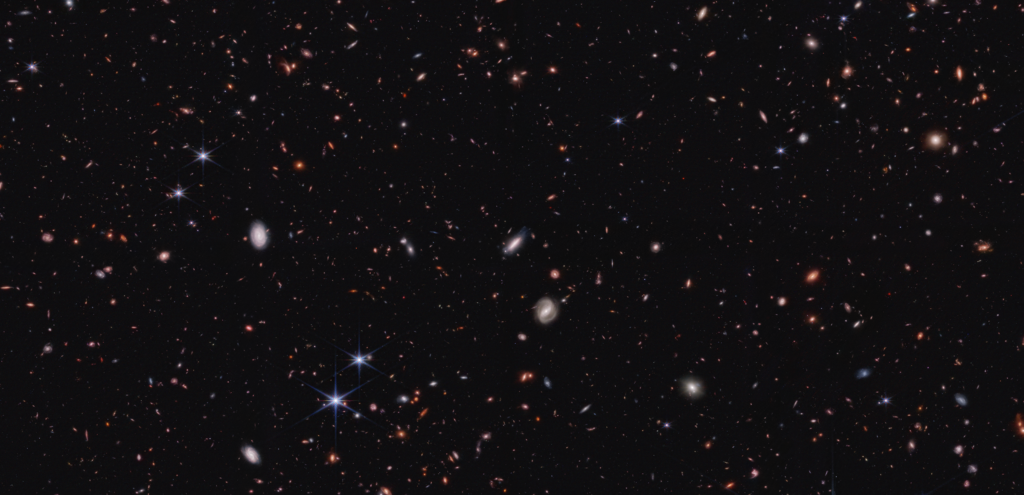 The blackness of space is interrupted by a smattering of tiny, colorful blobs