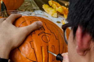 A U.T. Austin student carving a Longhorn themed jack-o’-lantern.