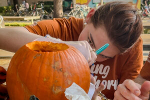 A U.T. Austin student carving a Longhorn themed jack-o’-lantern.