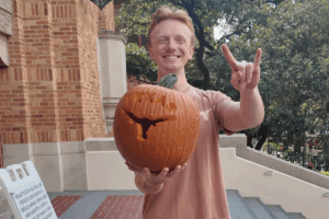 A student holding a carved pumpkin.