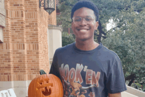 A student holding a carved pumpkin.