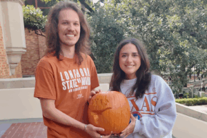 Two students holding a carved pumpkin.