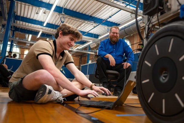 Student and professor working on a laptop in a robotics lab