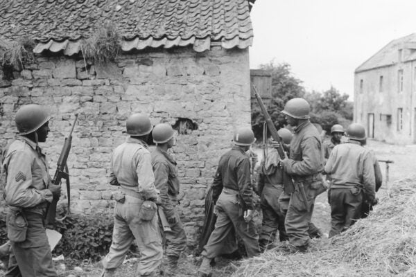 111-SC-190120_NARA_Platoon of Negro Troops Surrounds a Farm House in a Town in France, as They Prepare to Eliminate a German Sniper Holding up an Advance, Omaha Beachhead (1)