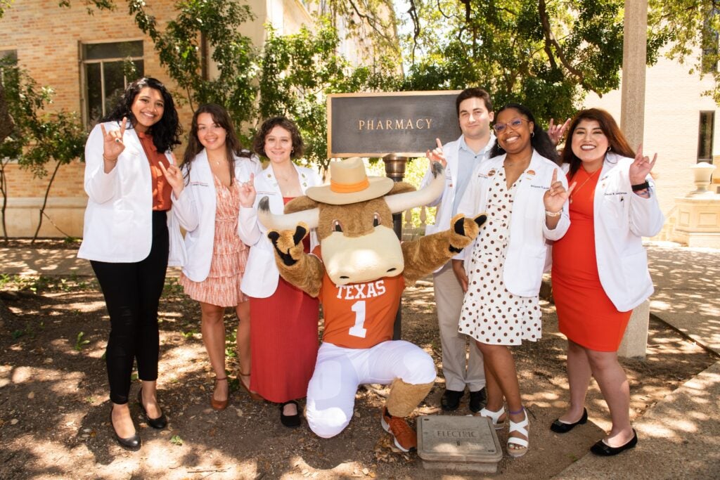 Six students stand with Hook Em next to College of Pharmacy sign