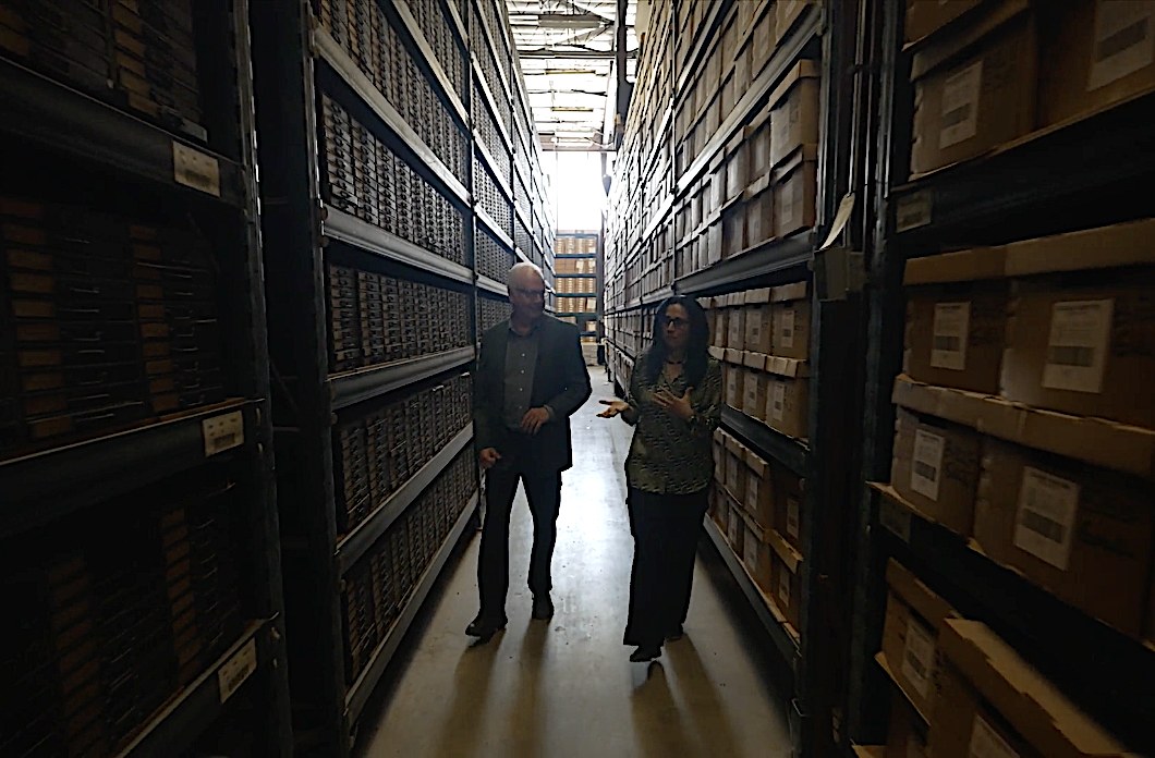 People walking between isles of shelves with boxes
